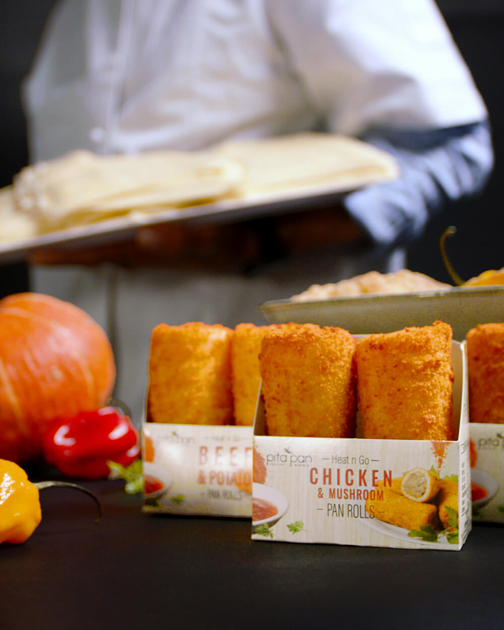 Chef walks in background out of focus behind assortment of Pan Rolls and food decorations.